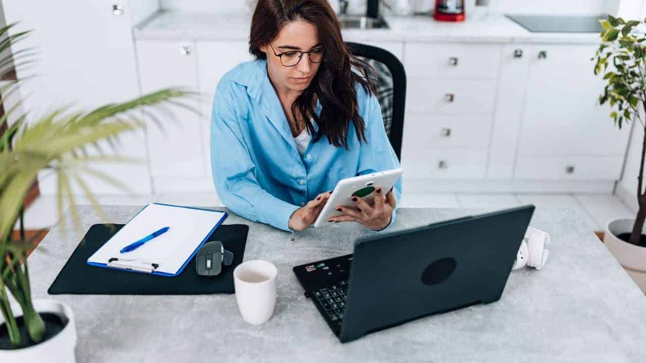 a woman sitting at a desk with a laptop and a tablet