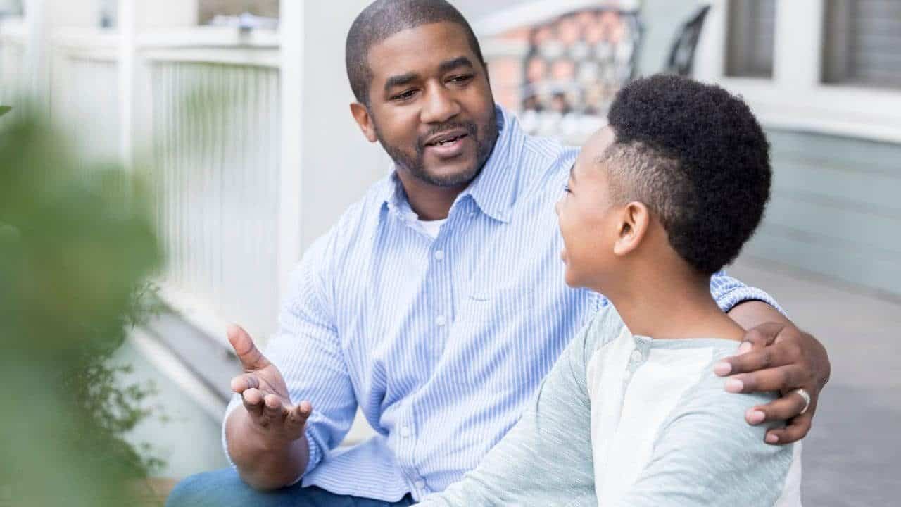 a man and boy sitting on a bench talking