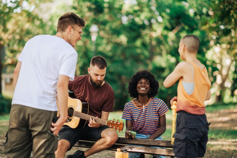 Multicultural street performers having rehearsal in public park.