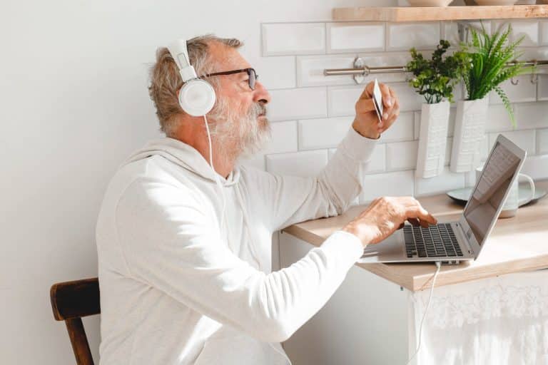 Senior elderly man at laptop paying with credit card for online shopping - copy space and place for